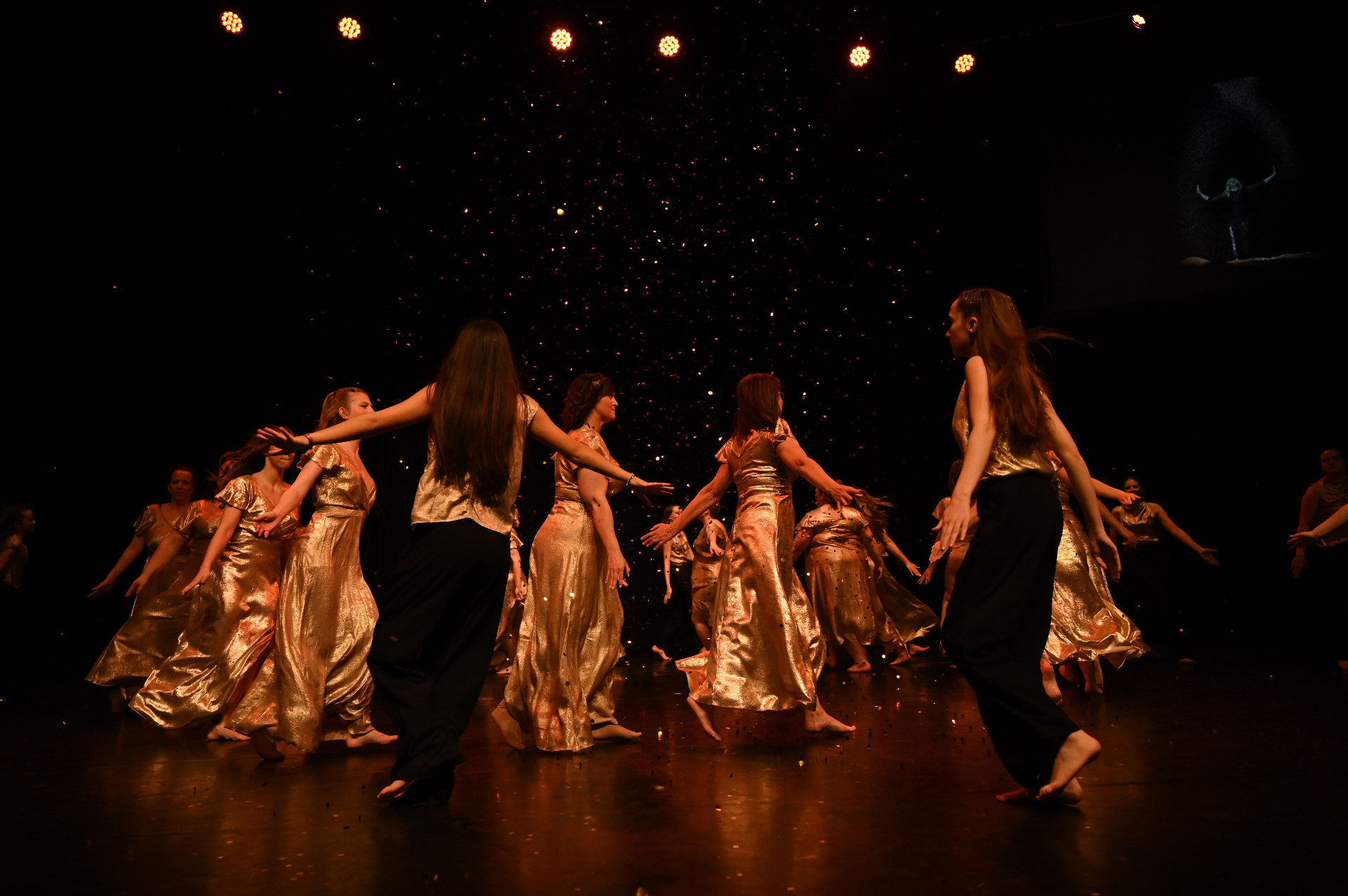 Troupe de danseuses de Danse et Vous en robes dorées sur scène, sous une pluie d'étincelles
